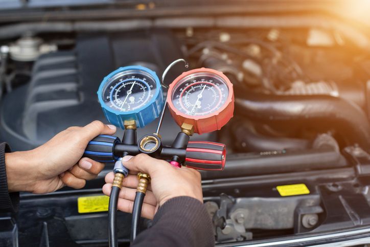 A Man Holding Two Gauges In Front Of A Car Engine — Wilbraham, MA — Ken’s Automotive