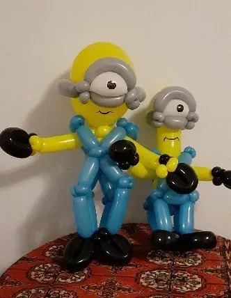 Two minions made out of balloons are sitting on a table.