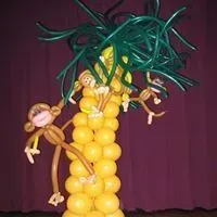 A palm tree made out of balloons with monkeys hanging from it.