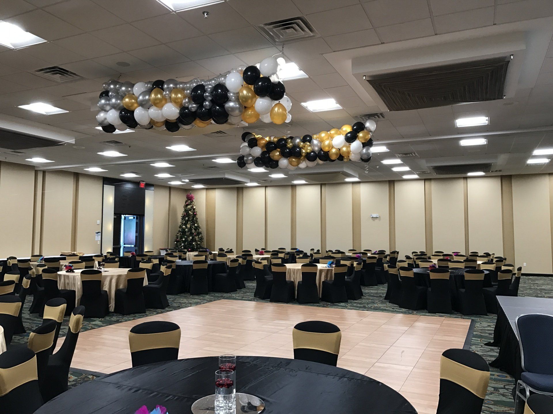 A large room with tables and chairs and balloons hanging from the ceiling.