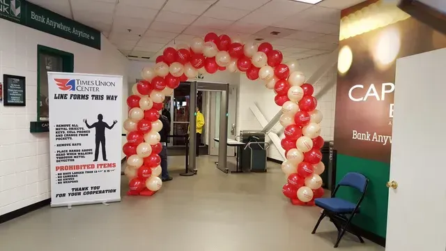 A large arch made of red and white balloons in a room.
