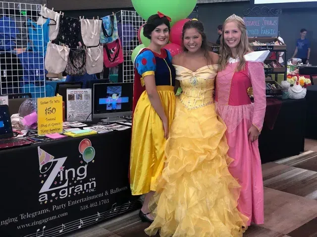 Three women dressed as snow white , belle and aurora are posing for a picture.