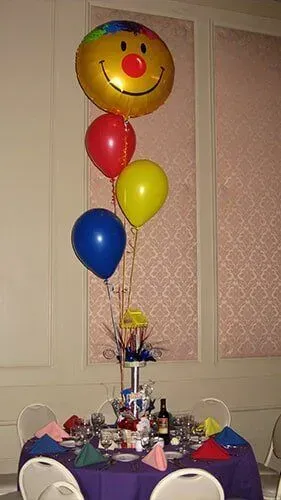 A table decorated with balloons and a smiley face balloon.