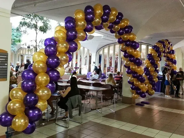 A purple and gold balloon arch in a room