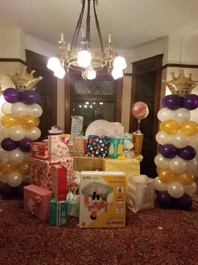 A room filled with gifts and balloons and a chandelier.