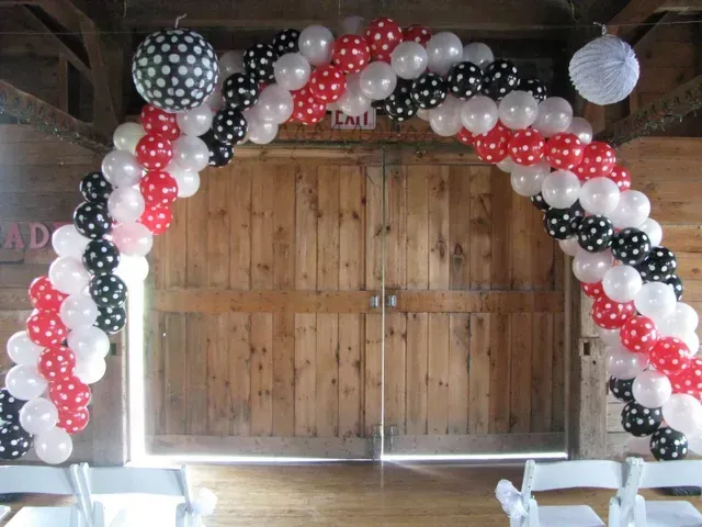 A wooden door is decorated with red white and black balloons