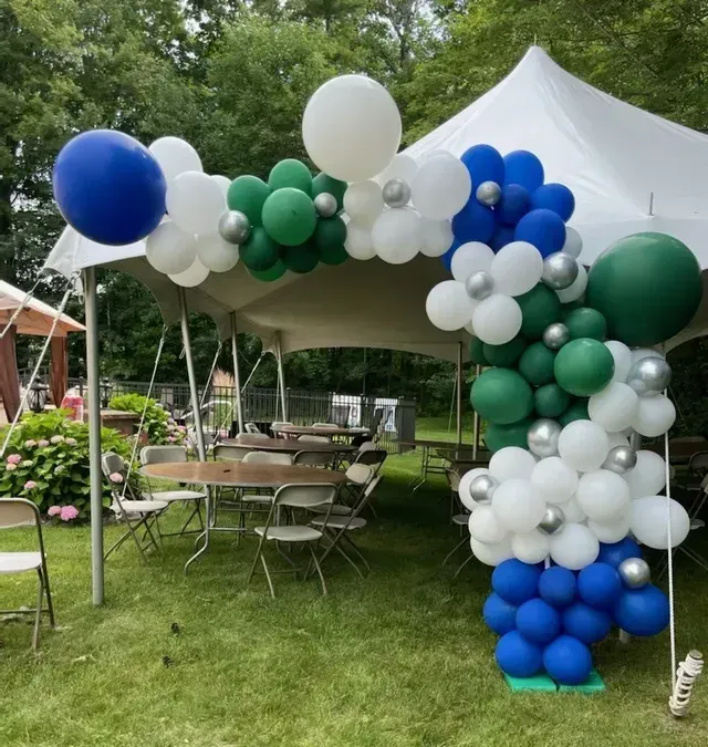 Blue white and green balloons in front of a white tent