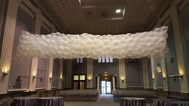 A large room with tables and balloons hanging from the ceiling