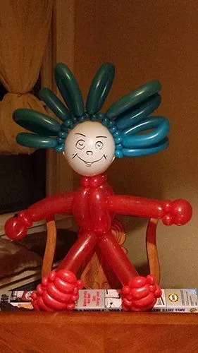 A person made out of balloons is sitting on a table.