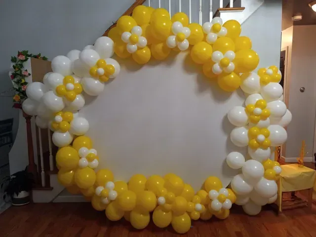 A room decorated with yellow and white balloons and flowers.