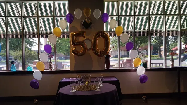 A room decorated with balloons and a table for a 50th birthday.
