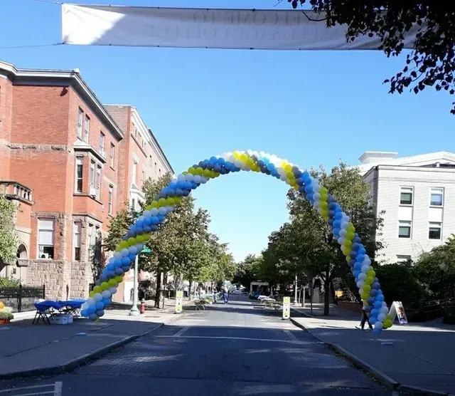 A blue yellow and white balloon arch in the middle of a street
