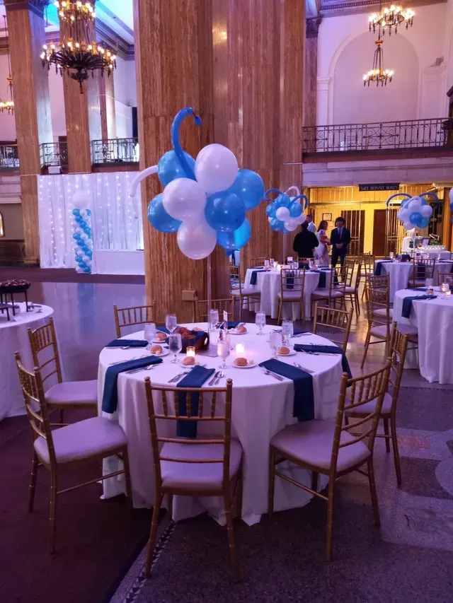 A room filled with tables and chairs with blue and white balloons on them