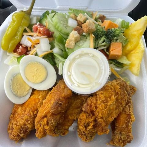 A styrofoam container filled with fried chicken eggs and vegetables