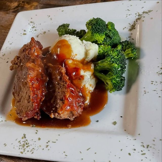 A white plate topped with meatloaf broccoli and mashed potatoes