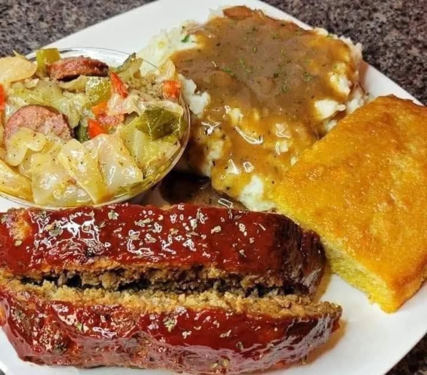 A white plate topped with meat loaf mashed potatoes and cornbread