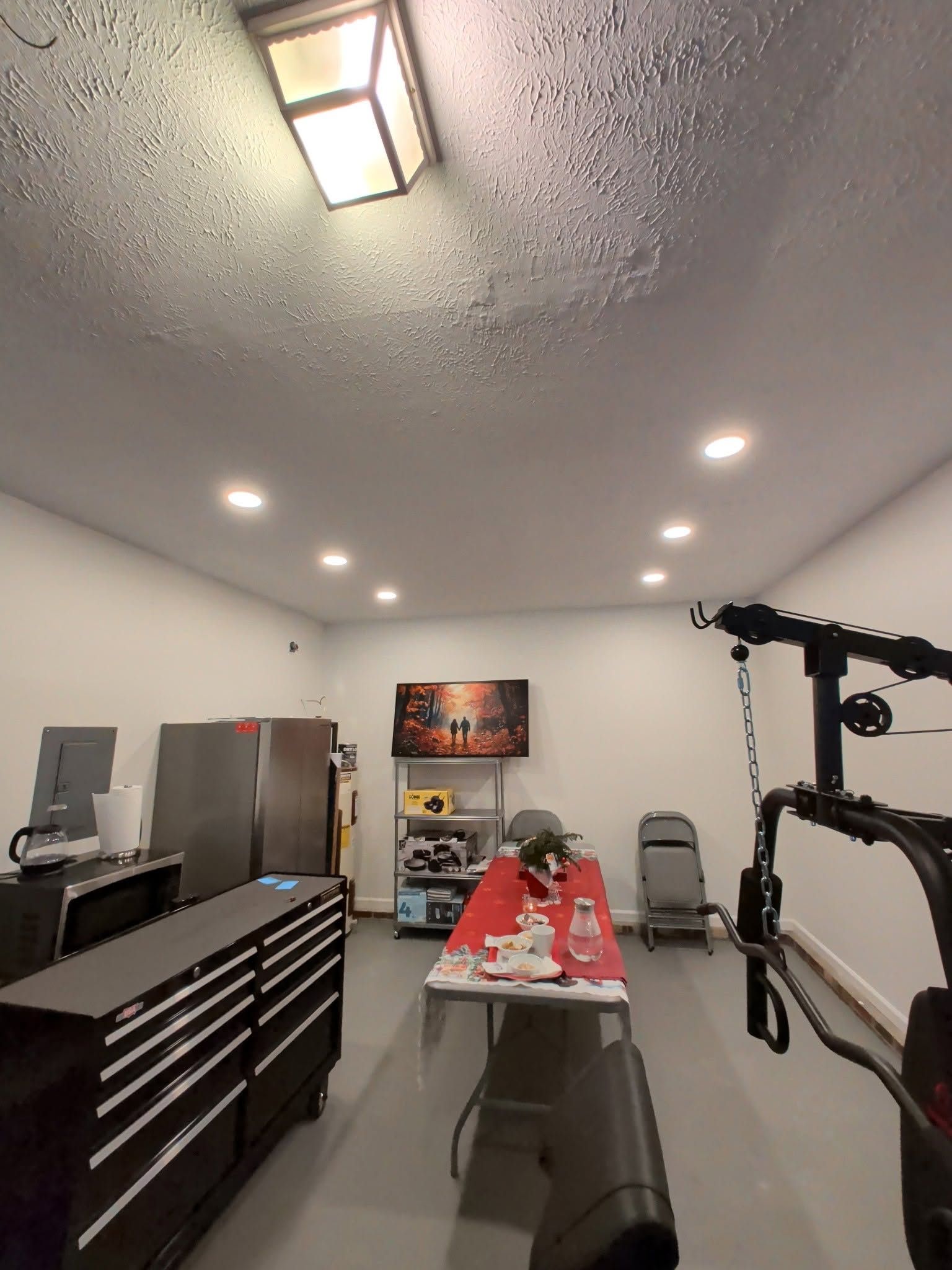 Home gym room with equipment, bench, cabinets, wall TV, and ceiling lights