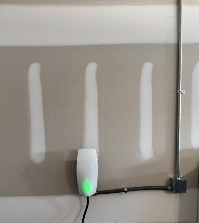 Wall with three white vertical paint strips and a small device with a green light near the bottom center