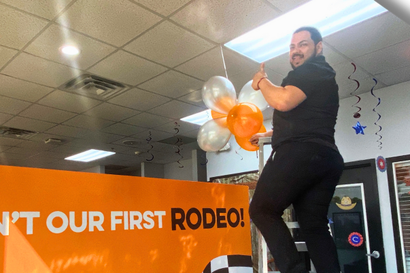 a man is holding balloons in front of a sign that says 