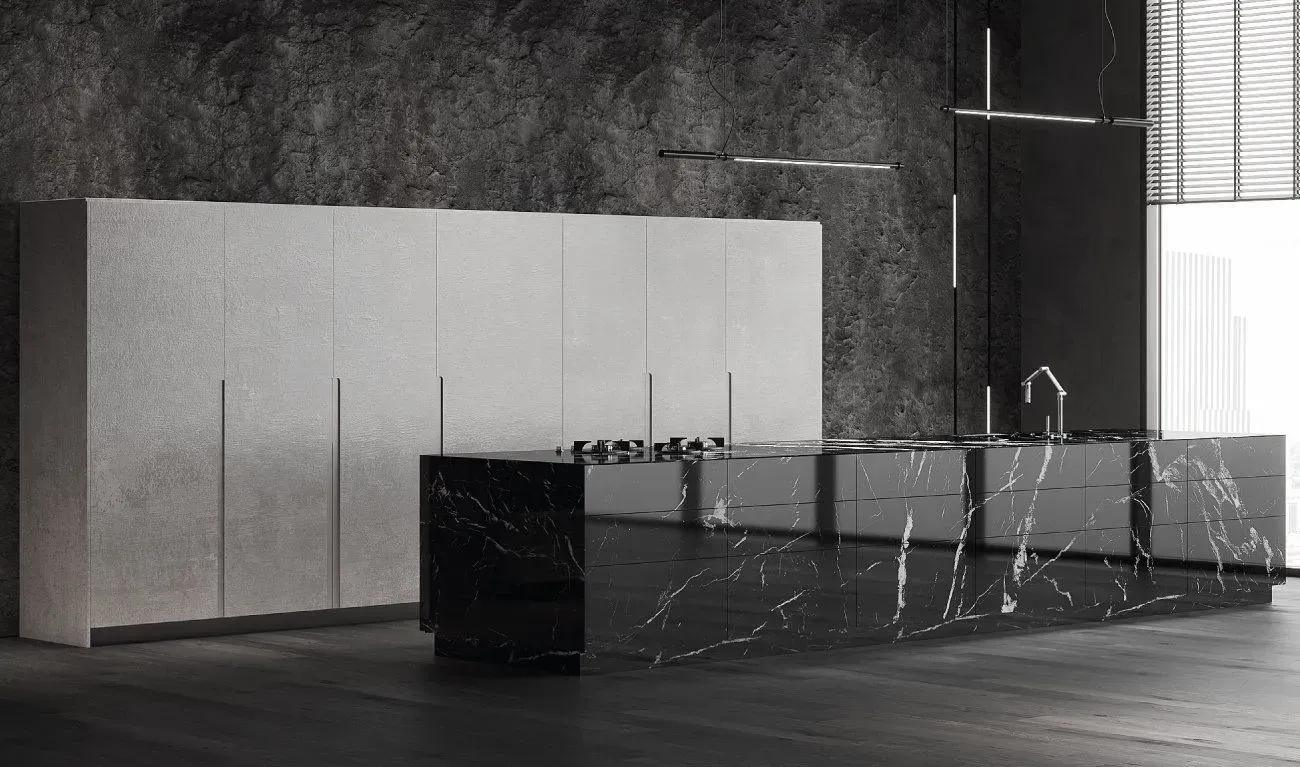 Modern kitchen with dark stone island, light cabinets against a stone wall, dark flooring.