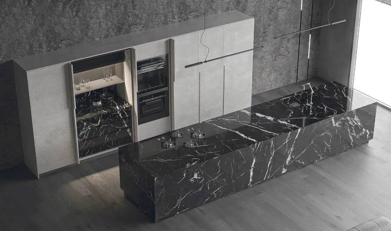 Modern kitchen with black marble island and light gray cabinetry against a gray stone wall.
