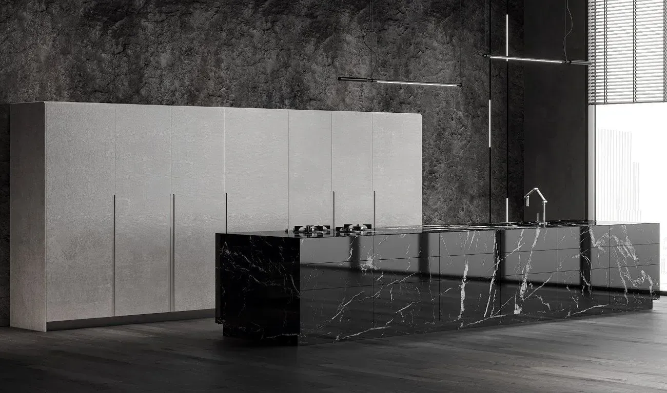 Modern kitchen with black marble island and white cabinetry against a stone wall.