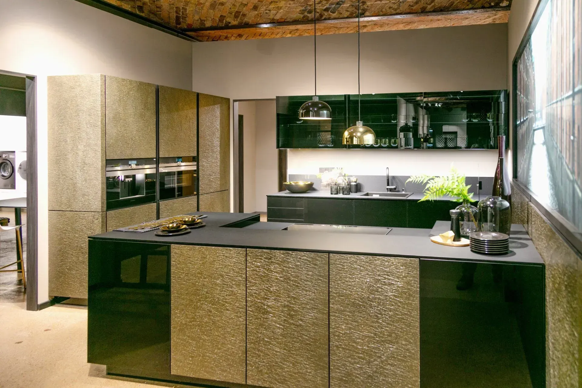 Modern kitchen with gold speckled cabinets, black island, and dark accents.