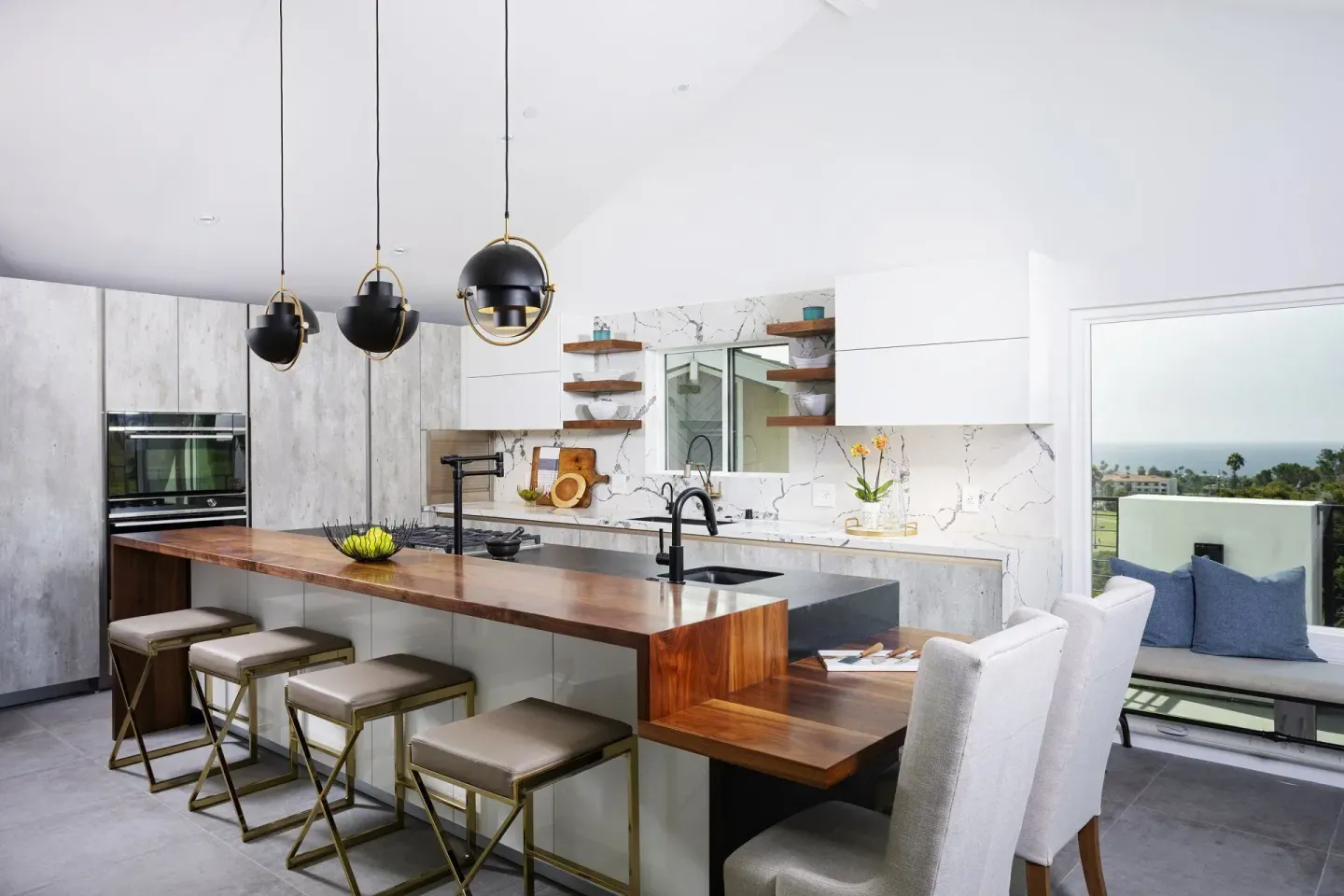 Modern kitchen with white cabinetry, marble backsplash, wooden island with bar stools and pendant lights.