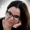 אישה עם שיער כהה ומשקפיים נשענת על ידה ומביטה בצופה.
