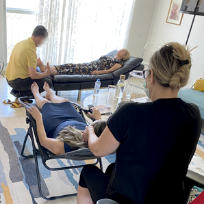 אנשים מקבלים עיסוי בחדר מואר. אדם אחד מקבל עיסוי כף רגל, אחר עיסוי צוואר, ושלישי נח.