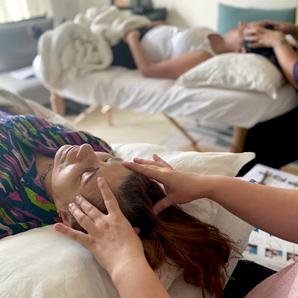 שני אנשים מקבלים עיסויי ראש בשכיבה. אחרים נמצאים ברקע.