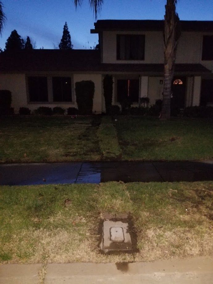 Two-story house with a small front yard, grass path leading to the door. Dark sky at dusk.