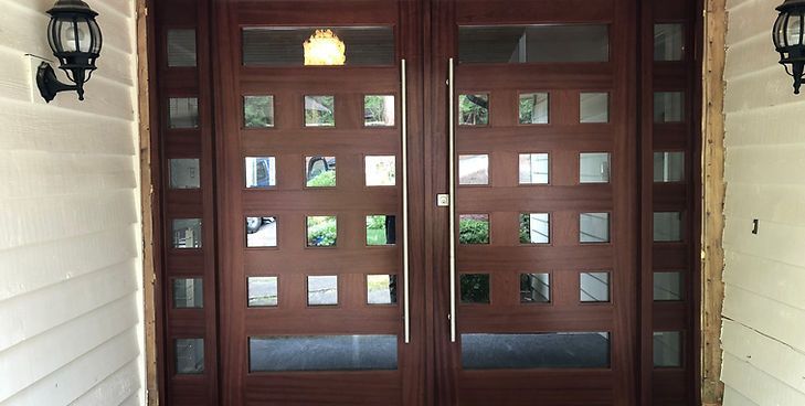 A dark wood double front door featuring a grid of small square windows and tall, vertical silver handles.