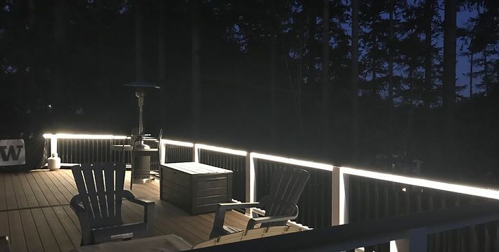 An outdoor deck at dusk, illuminated by glowing LED strip lights installed along the dark railings.