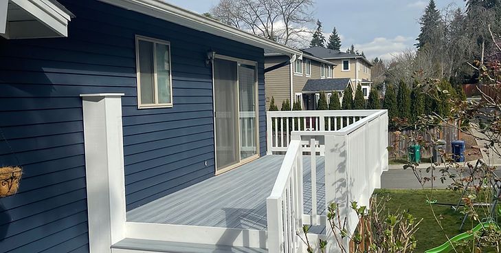 A blue house exterior featuring a light gray deck with white railings and a sliding glass door.