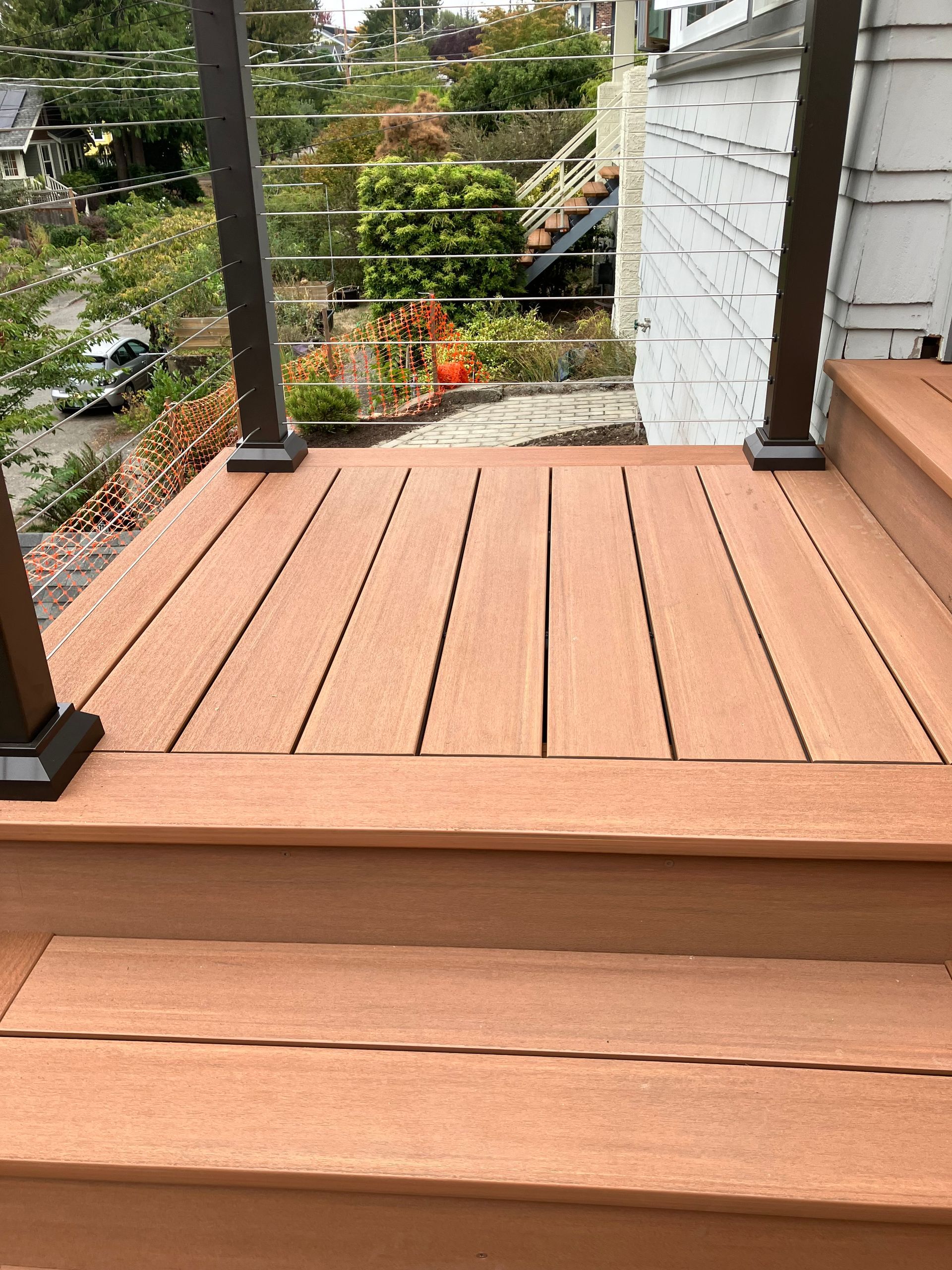 A set of outdoor composite steps with dark metal railings leading up to a house entrance.
