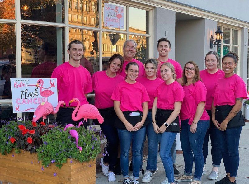 A group of people wearing pink shirts are standing in front of a building.