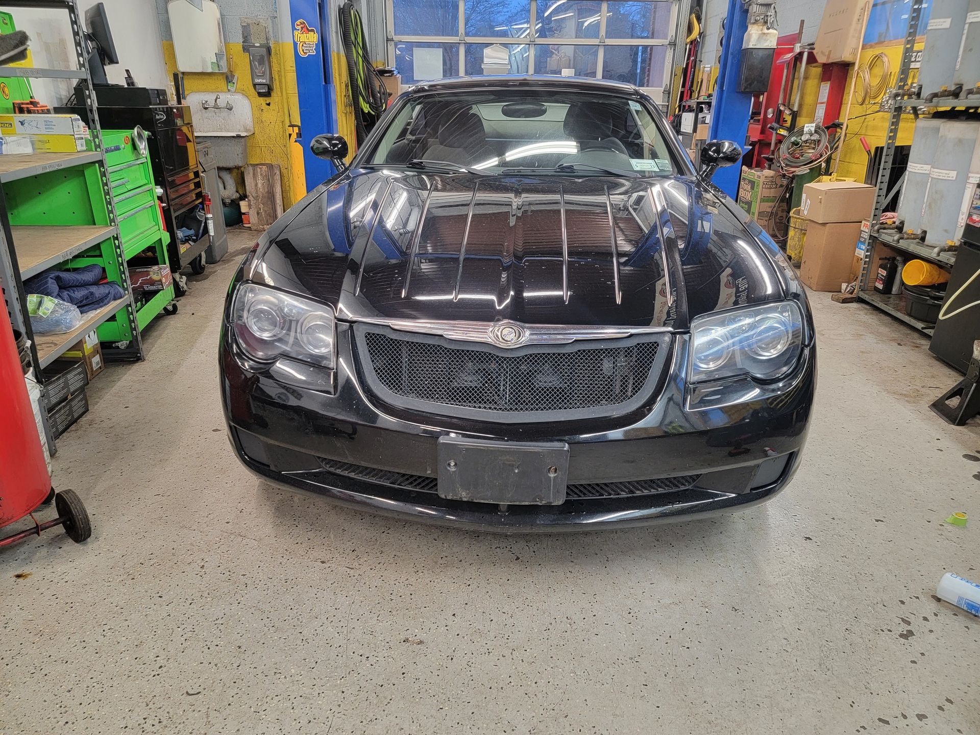 Black Chrysler 300 sedan in a mechanic's garage, facing forward.