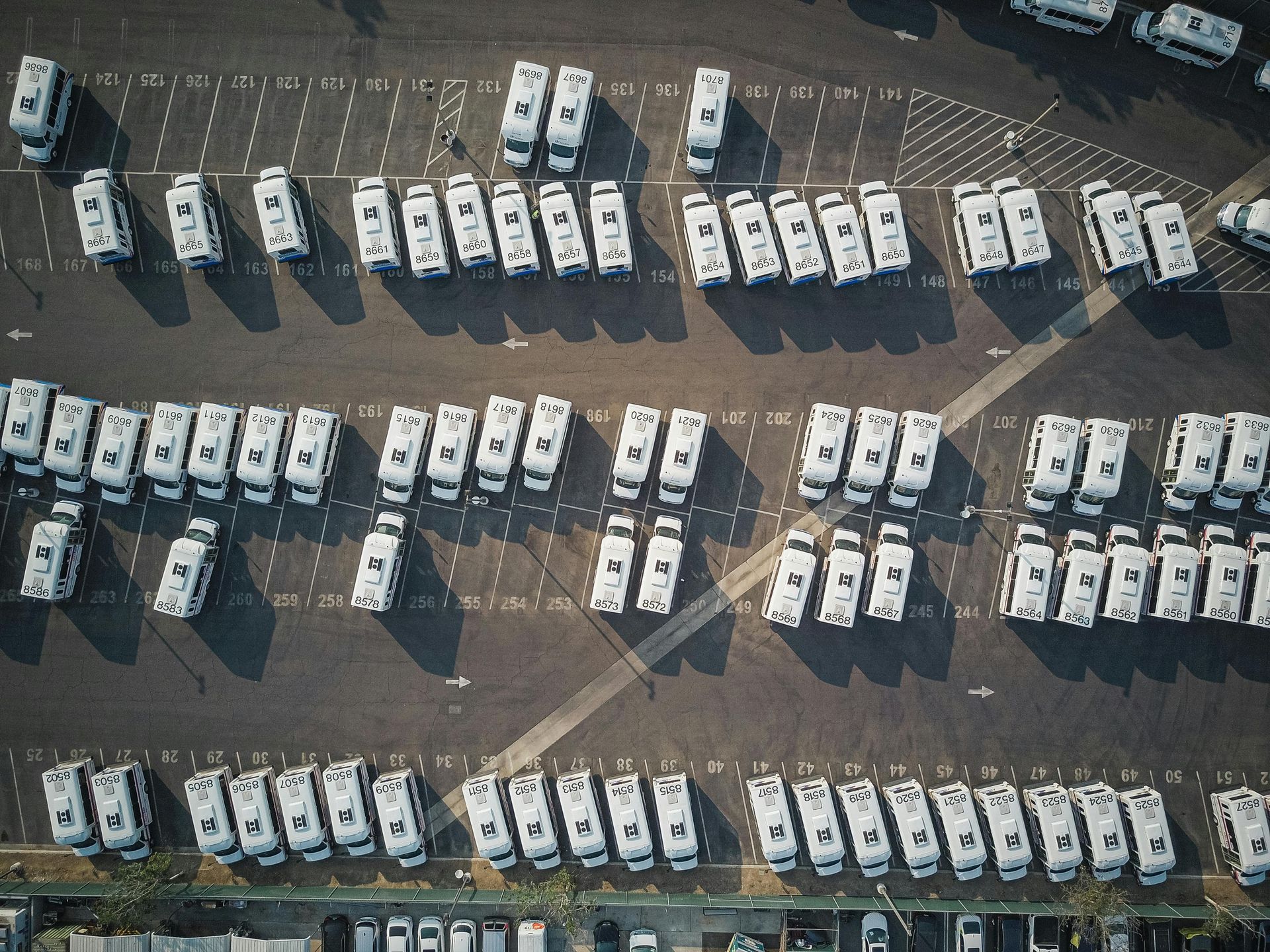Overhead view of a parking lot filled with rows of white RVs parked in an organized fashion.