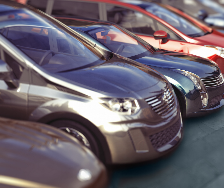 Row of parked cars, including a silver sedan in front and red vehicles behind.
