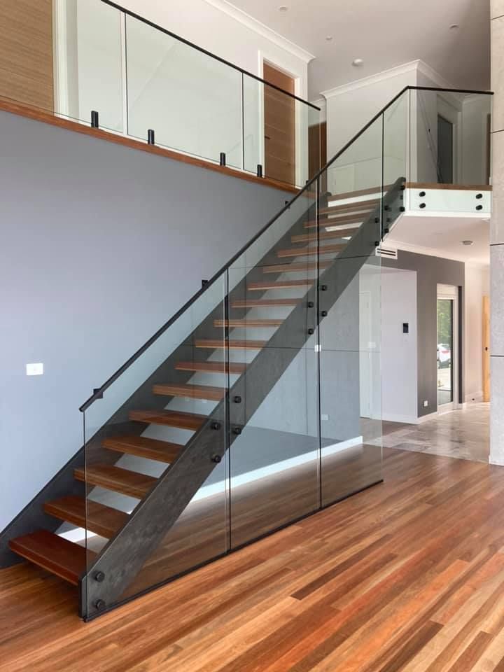 A Wooden Staircase With A Glass Railing In A House — Lamont Builders In Woonona, NSW