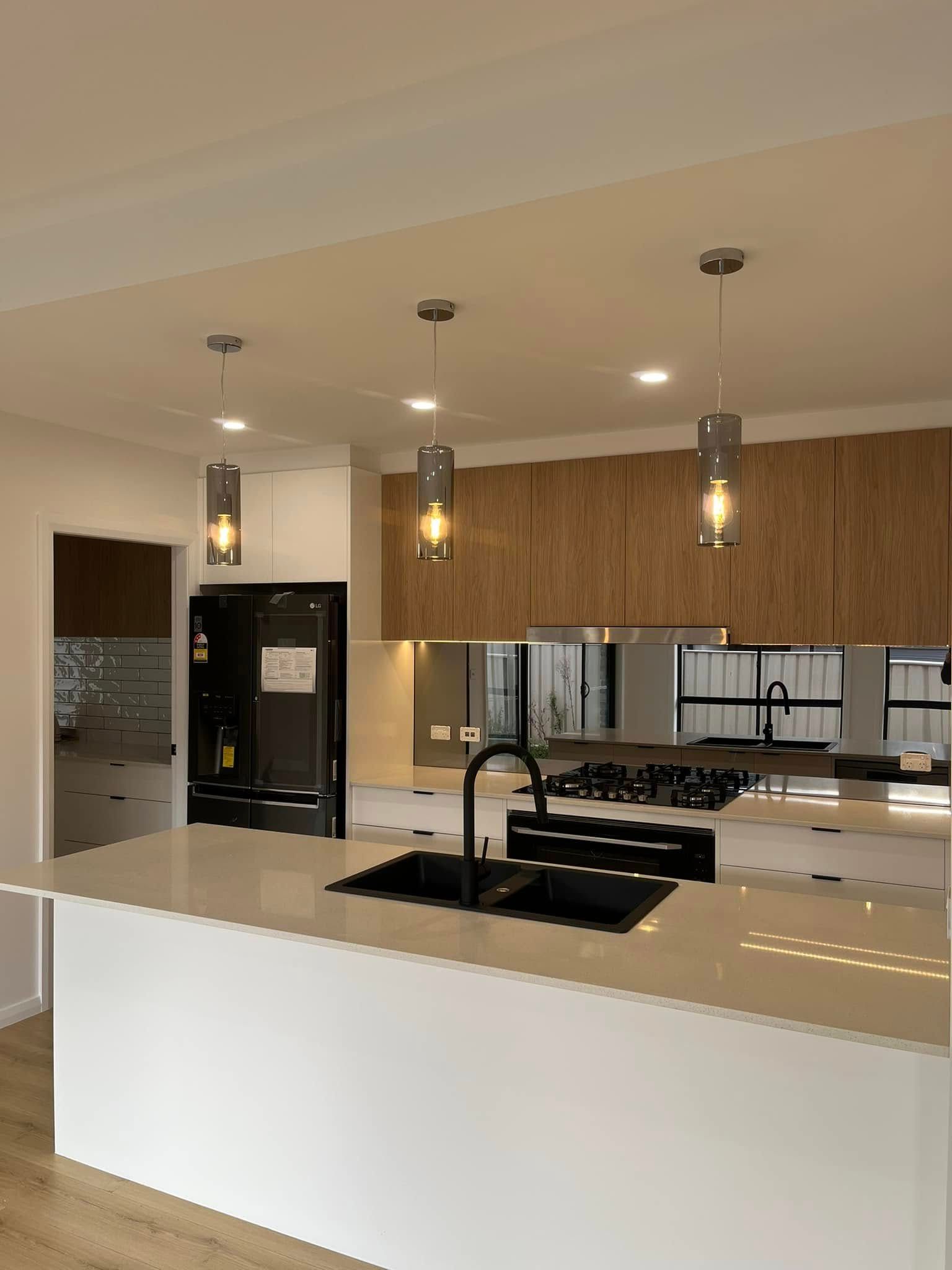 A Kitchen With A Large Island , Sink , Stove And Refrigerator — Lamont Builders In Kiama, NSW