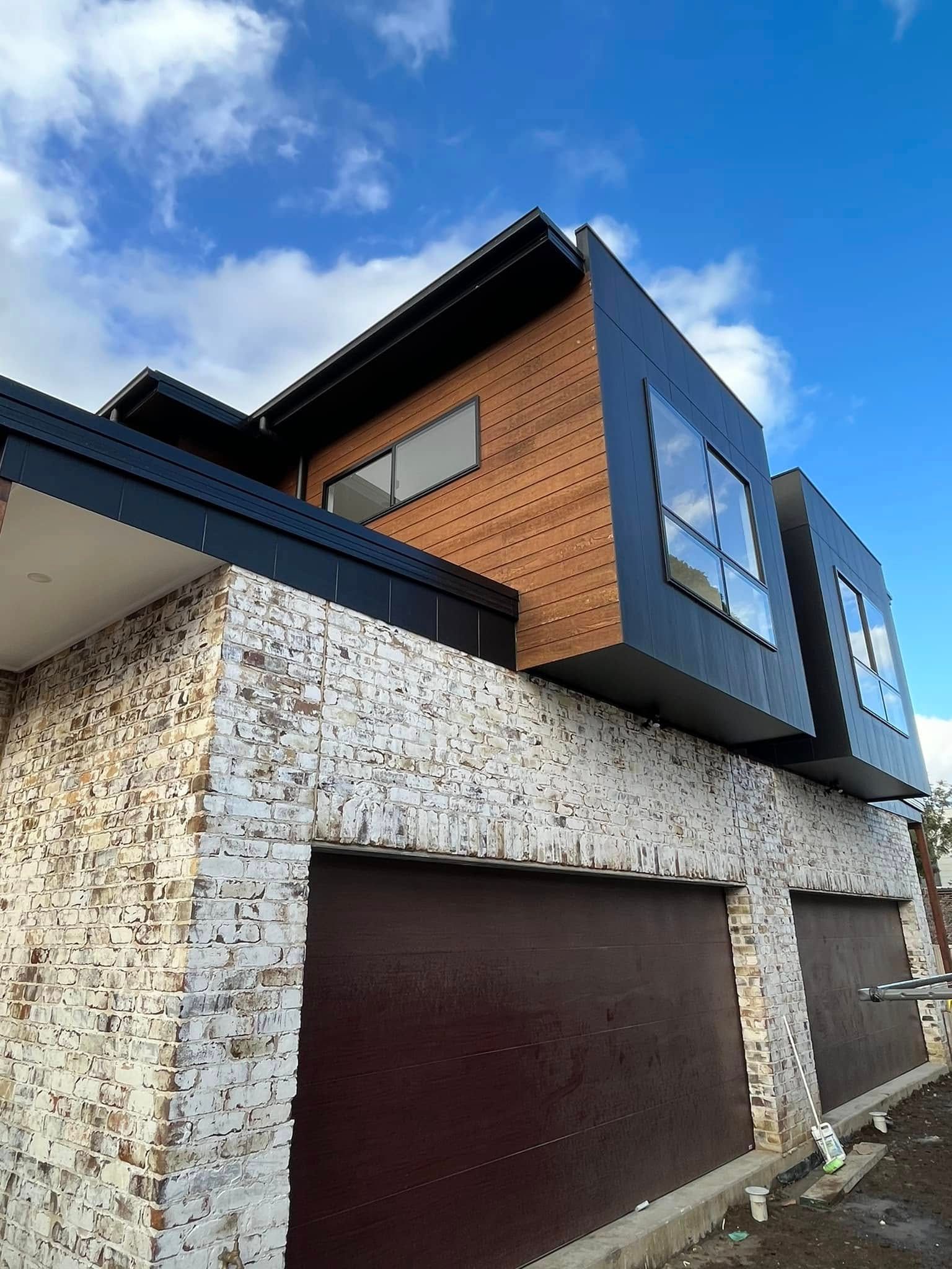 A Large House With A Lot Of Windows And Garage Doors — Lamont Builders In Woonona, NSW