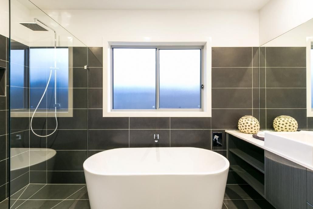 A Bathroom With a Bathtub, Sink, Shower and Window — Lamont Builders In Woonona, NSW
