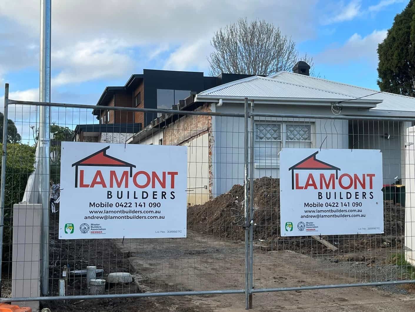 Two Lamont Builders Signs Are On A Fence In Front Of A House Under Construction — Lamont Builders In Woonona, NSW