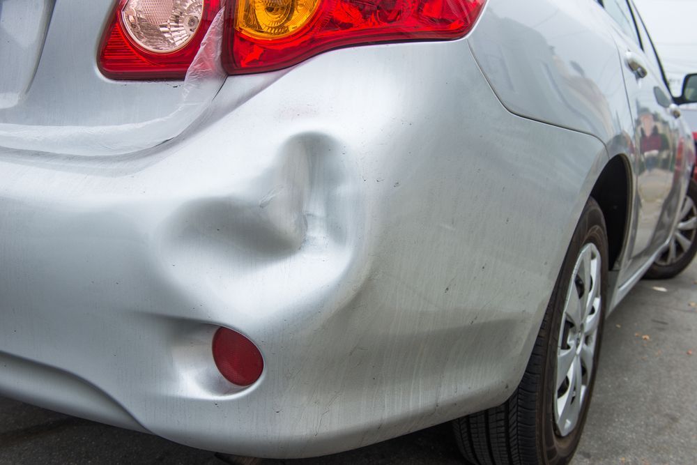 A Silver Car With a Damaged Bumper is Parked on the Side of the Road — Greg Hennessey Smash Repairs In Woolgoolga, NSW