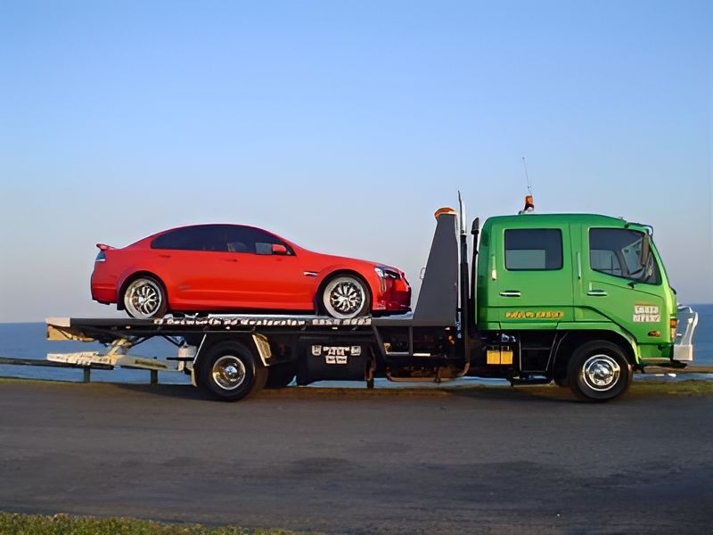 A Red Car is Sitting on Top of a Green Tow Truck — Greg Hennessey Smash Repairs In Woolgoolga, NSW