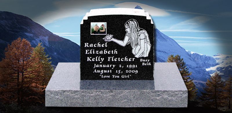 A black headstone with name, dates, photo, and drawing. Set on a gray base with a mountain backdrop.