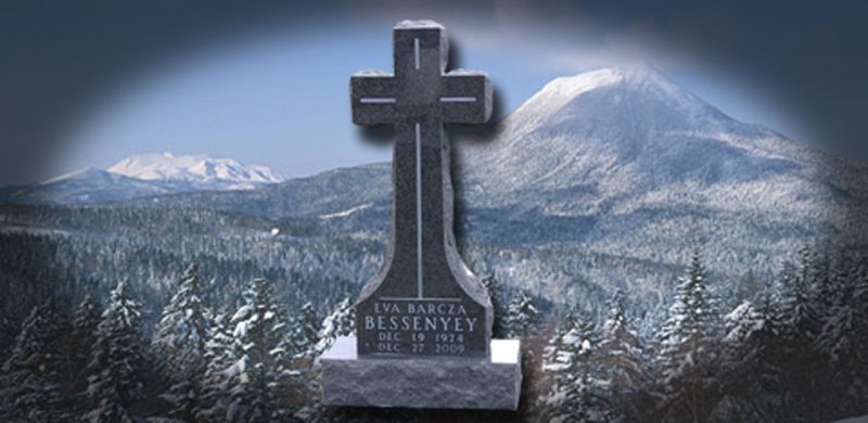 Gravestone with cross in a snowy mountain landscape.