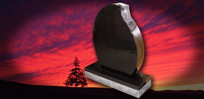 Black headstone against a colorful sunset.